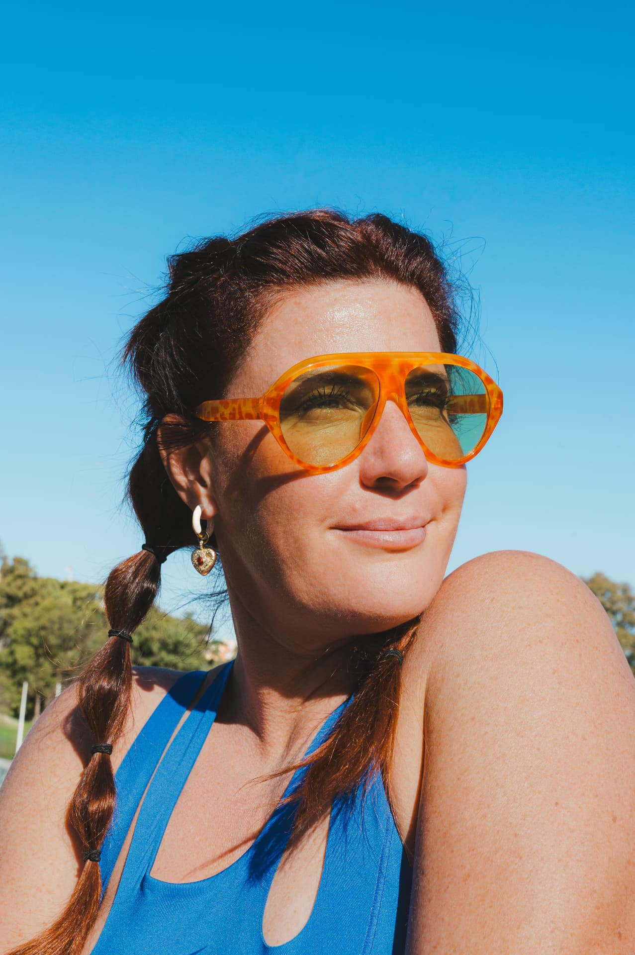 Juline Mouget avec des lunettes de soleil orange, sous un ciel bleu